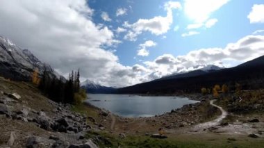 Time-lapse in a Canadian nature park near a lake, in the autumn, people moving around, clouds changing col