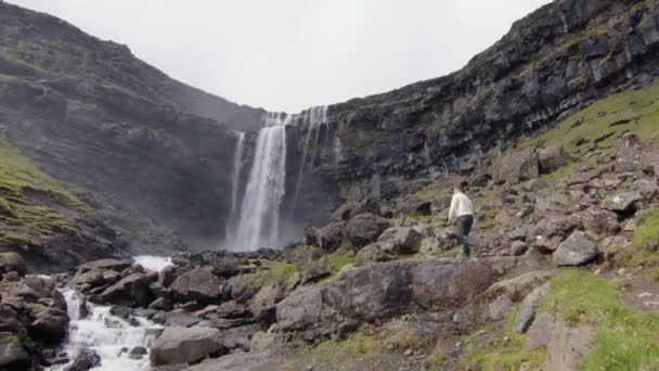 デンマークのフェロー諸島の滝に向かって歩く人 — ストック動画