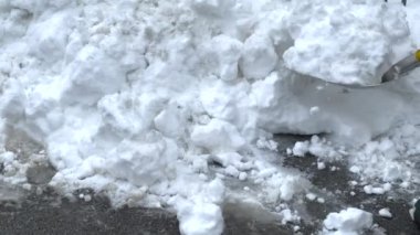 A man cleans the road in winter with a shovel