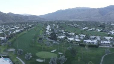 An aerial view of buildings and palm trees near green mountains