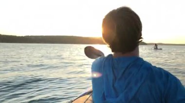 A young male in a boat rowing in the open sea on a sunny day