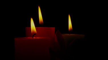 A closeup of burning candles against a black background