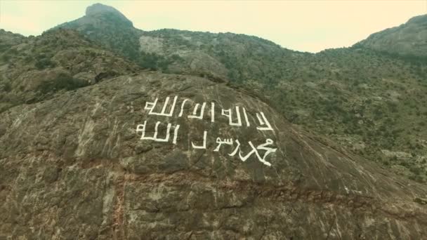 サウジアラビアの岩の多い山のドローンビュー 27年前に市民が山の上に 統一の旗 を書きました — ストック動画