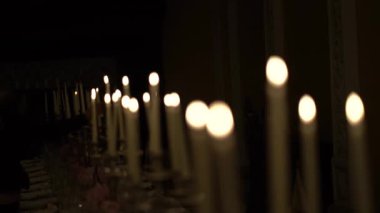 The rows of burning candles in the dark of the church on a bokeh background