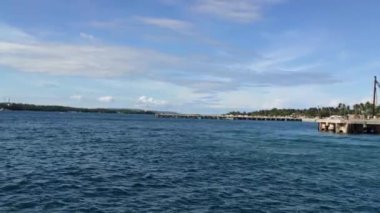 Okyanus dalgaları manzaralı bir tekne ve arka planda yeşilliklerle kaplı güzel tepeler.