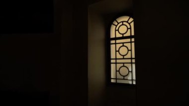 An eerie view of light reflecting behind te beautiful glass window of a dark room