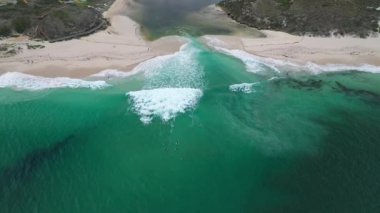 An aerial view of waves on a beach on a sunny day in Jindalee, Western Australia