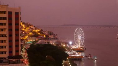 A timelapse of a city with evening turning to night - Ferris wheel by the sea in a luminous city at night