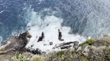 Yukarıdan gelen deniz dalgaları taşlara ve kayalara dokunuyor, mavi su.