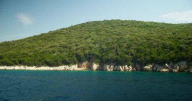 A beautiful view of a cliff with thick trees surrounded by water on a sunny day in Croatia