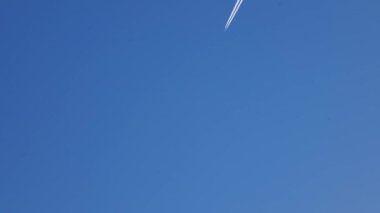 A low angle view of a white plane flying in the sky on a sunny day