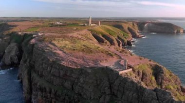 A scenic shot of a high mountain with buildings surrounded by the ocean