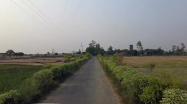 An aerial view of a road near a green meadow in the countryside