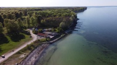 The 4K aerial drone footage moving along the coastal line of the beach with a resort house and turquoise calm ocean view