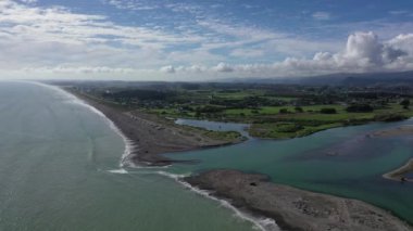 aerial video of otaki river and tasman sea looking north and seeing interaction of river and sea. Full tide
