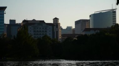 A scenic shot of the city buildings, trees, and a lake