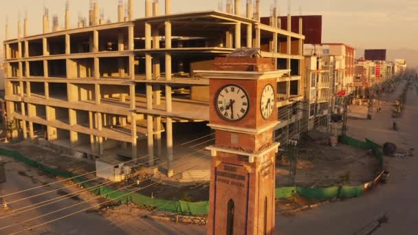 パキスタンのラワルピンディに建設中の車と小さな時計塔のドローンショット — ストック動画