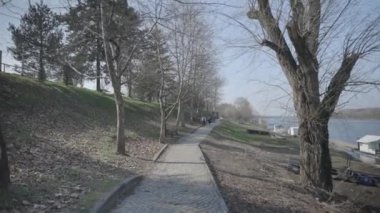 A beautiful shot of people walking on a pathway with trees in Public park Ficibajer at River Sava in Brcko, Bosnia and Herzegovina