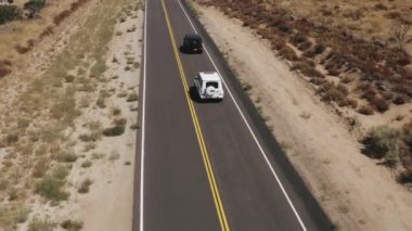 A drone shot of black and white Mercedes-Benz G-class cars driving in the Palmdale desert
