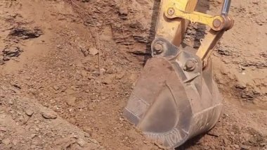 Bir kazıcı Moorum toprağını inşaat alanındaki bir traktöre yüklüyor. İnşaat işi için taş kırma. JCB makinesi çalışıyor.
