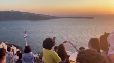 A beautiful shot of tourists in Santorini during the summer watching the sunset over sea, Greece