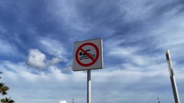 No swimming warning sign with blue sky outdoors