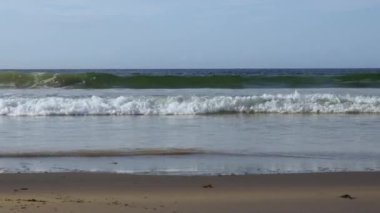 A beautiful view of the ocean waves hitting the sandy beach