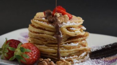 A closeup shot of delicious pancakes with strawberries, chocote and sugar powder