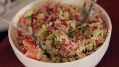 Close up of a bowl of couscous salad being mixed in a bowl