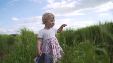 A cute little baby girl walking in a rural field in slow motion