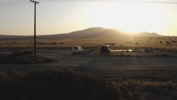 天気の良い日に砂漠の道路上の黒と白の車の空中ショット — ストック動画