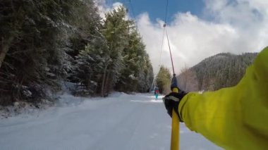 A young man snowboarding on a ski track among pine trees at a ski resort