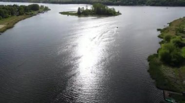 Overview of the Zegrzynskie lake, a little island in the middle. The sun reflected in the water, a few boats, and a forest in the background, Poland