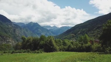 An aerial view of a green valley with beautiful mountains under the bright blue sky