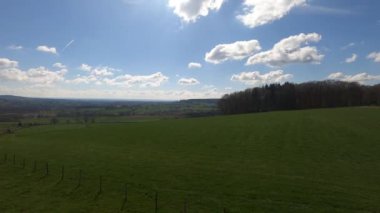 A time-lapse of clouds in the sky over a meadow in the daytime.