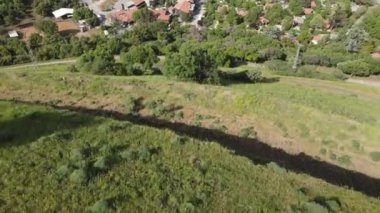 An Aerial top view drone footage of a beautiful small village under a high hill surrounded by trees