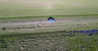 Aerial view of a blue truck by a dirt truck in the middle of the field, at the edge of a stream.