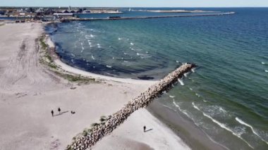 An aerial shot of a beach with a blue sea waving in sunny weather