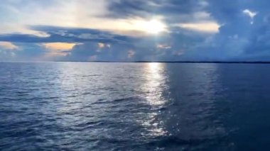A scenic view of the seascape against cloudy dusk sky at sunset as seen from a moving boat