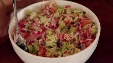 Close up slow motion shot of a bowl of couscous salad being tossed