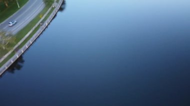 An aerial footage of a beautiful cityscape with a wide lake at sunset