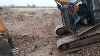 Hindistan 'daki inşaat alanında yük taşı ve toprak moorumunu traktöre dönüştüren bir kazıcı.