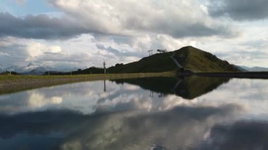 The beautiful footage of Leogang Lake reflecting the cloudy sky. Austria, Alps.