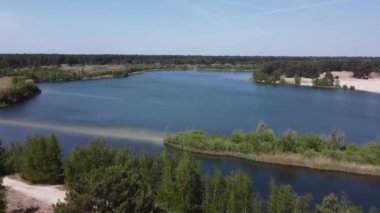 An aerial slow movement around lake surrounded by dense forest in Belgium