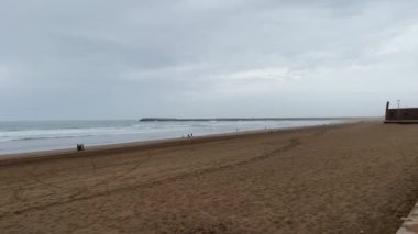 Few people walking in the beach with a cloudy sky