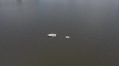 An aerial 180 degree drone footage of a boat with a float attached in the lake