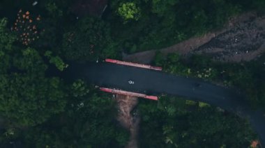 An aerial view of a road leading through green forests and fields