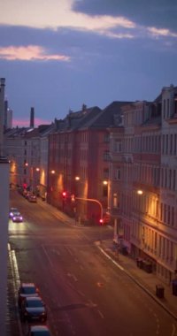A vertical time lapse of the traffic on the street between old buildings while getting dark