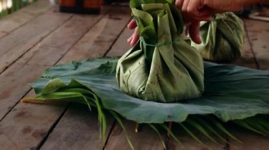 Unpacking khmer food takeaway packed in eco-friendly lotus leaves in Siem Reap, Cambodia shot in slow motion