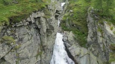 A drone shot over a beautiful waterfall flowing between green rocky mountains